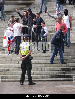 Ein Polizist steht vor einer Gruppe von jungen Mitgliedern der English Defence League, wie sie anti-faschistischen Demonstranten während einer Protestaktion gegen eine muslimische Schule zu, die verhöhnen soll in Portsmouth, England Stockfoto