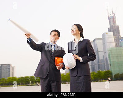 asiatische Geschäftsleute mit Sicherheit Hüte und Blueprint. Stockfoto