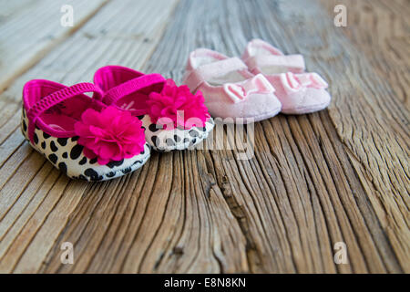 Ausgefallene und farbenfrohe Sweetbaby Schuhe auf dem Holztisch Stockfoto