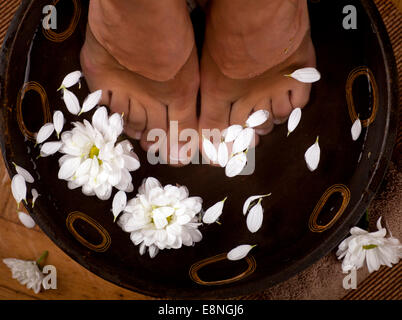 Weibliche Füße in foot Spa Schale mit Blumen und Handtücher Stockfoto