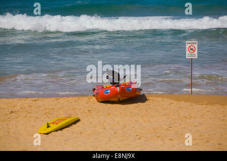 Surfen Sie lebensrettende Club Schlauchboot und Surfbrett am männlichen Strand, mit Schild Warnung vor starken Strömungen, Sydney, Australien Stockfoto