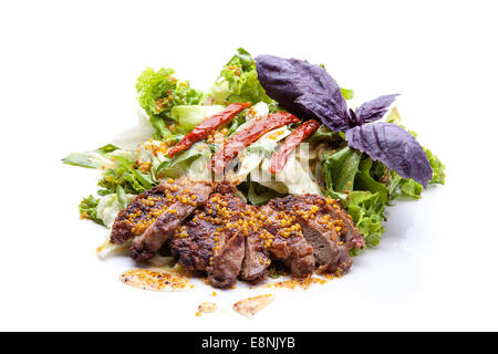 Stücke von gegrilltem Fleisch mit Dijon Senf und Salat auf weißem Hintergrund Stockfoto