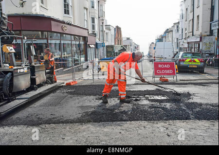 Eine Autobahn Wartung Worker flickt ein Schlagloch in einer Straße in Brighton. Stockfoto