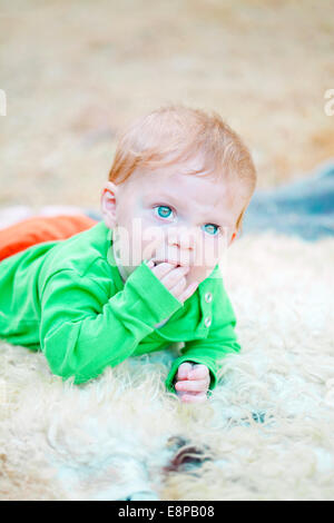 Closeup Portrait von einem niedlichen blonden Baby seine Finger beißen, während starrte neugierig Stockfoto