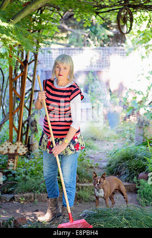 Ältere Frau im Garten mit Rechen Stockfoto