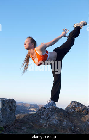 Junge Frau stehen in Arabeske Position auf Felsen Stockfoto