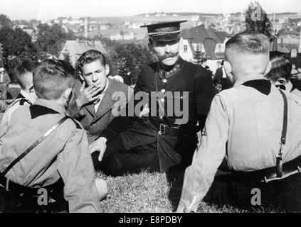 Das Nazi-Propagandafild zeigt einen Sudetenland-Polizisten, der aus der Tschechoslowakei geflohen ist und im Vorfeld des Münchner Abkommens im September 1938 in Baerenstein, Deutschland, mit Hitlerjugend sprach. Der ursprüngliche Text eines Nazi-Nachrichtenberichts auf der Rückseite des Bildes lautet: " Sudetendeutsche, die vor dem tschechischen Terror fliehen. Dieser Polizist floh aus Weipert mit anderen Sudetendeutschen, die eine tschechische Polizeiuniform trugen, und erzählt diesen Hitler Youth (in Baerenstein) seine schockierenden Erfahrungen. Fotoarchiv für Zeitgeschichtee - KEIN KABELDIENST Stockfoto