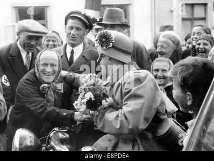 Das Nazi-Propagandafilm zeigt den Empfang deutscher Truppen durch sudetene Männer und Frauen in Egerland, Sudetenland (Tschechische Republik) im Oktober 1938. Der ursprüngliche Text des Nazi-Nachrichtenberichts auf der Rückseite des Bildes lautet: "Bewegende Freudenkundgebung in Egerland. Für die deutschen Truppen, die vom Führer, von den Sudetendeutschen auf ihrem friedlichen marschierten Weg zur Befreiung des Sudetenland befohlen wurden, wurde ein fast unbeschreiblicher Empfang vorbereitet. Unser Bild zeigt eine alte Sudetendeutsche Frau aus Bergdorf, die freudig eine Blume an die ankommenden deutschen Truppen überreicht." Fotoarchiv für Zeitgeschichtee - KEIN WI Stockfoto