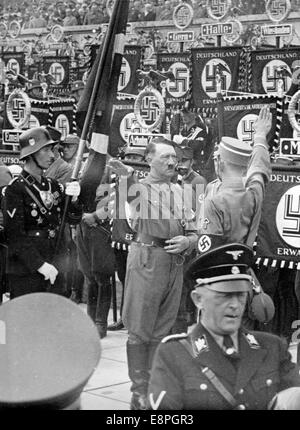Nürnberg Rallye 1937 in Nürnberg, Deutschland - die neuen Standards sind mit "Blut-Flagge" von Adolf Hitler während der großen Appell der Sturmtruppe (SA), Schutzstaffel (SS), nationale sozialistische Motor-Korps (NSKK) und nationalen sozialistischen Flyer Corps (NSFK) am Puitpoldarena auf dem Gelände der Nazi-Partei Rallye geweiht. Die "Blut" Fahnenträger Jakob Grimminger steht hinter Hitler. Neue Maßstäbe der SA und SS waren "geweiht" durch Berühren der Blut-Flagge, die angeblich in der gescheiterten Bier Hall Putsch vollzogen wurde. (Mängel in der Qualität durch das historische Bild kopieren) Foto: Berliner Ver Stockfoto