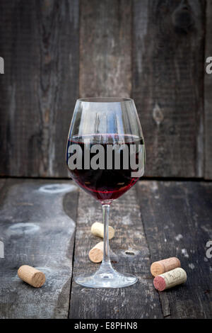 Glas Rotwein mit Korken auf alten Holztisch Stockfoto