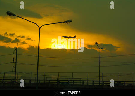 das Flugzeug ist mit dem Sonnenuntergang Hintergrund landen. Stockfoto