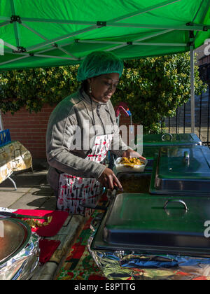 Karibische Frau Stall Inhaber in einem UK Bauernmarkt mit Ziege Curry und Reis zu verkaufen Stockfoto