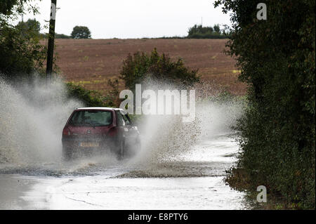 Essex, Großbritannien. Oktober 2014. Fahrzeuge fahren durch eine überflutete Straße in der Nähe von Buttsbury in Essex nach Nacht sintflutartigen Regen. Quelle: Gordon Scammell/Alamy Live News Stockfoto