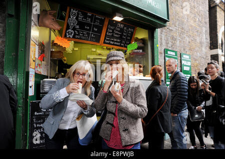 London Southwark UK - Frauen Essen zog Schweinefleisch Packungen an einem Stall in Borough Market London Southwark UK Stockfoto