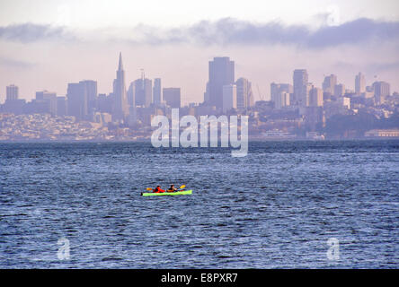 zwei Frauen paddeln Kajak an der San Francisco Bay mit Skyline im Hintergrund Stockfoto
