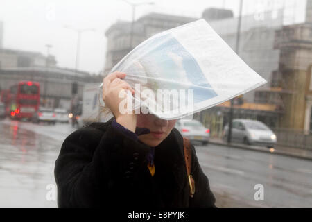 London, UK. 13. Oktober 2014.  Ein Fußgänger deckt den Kopf mit einer Zeitung aus dem anhaltenden Regen an einem verregneten Tag in der Hauptstadt Credit: Amer Ghazzal/Alamy Live-Nachrichten Stockfoto