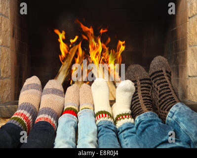 Füße von einer Familie tragen wollene Socken am Kamin Erwärmung Stockfoto
