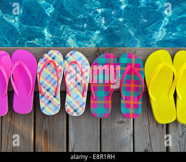 Bunte Flip-flops auf hölzernen Hintergrund in der Nähe der Pools Stockfoto