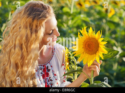 Glückliche junge Frau mit langen Haaren in dem Sonnenblumenfeld. Sommerspaß Stockfoto