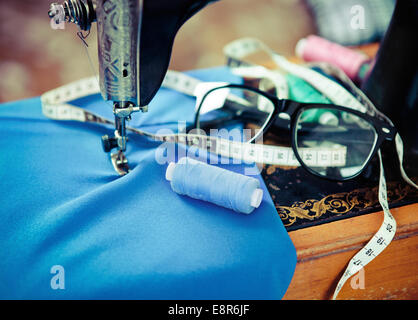 Retro-Nähmaschine mit Nähgarn, Stoffe, Nähnadeln und Gläser. Nahaufnahme Stockfoto