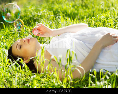 Schöne schwangere Frau entspannen auf dem Rasen im Frühjahr park Stockfoto