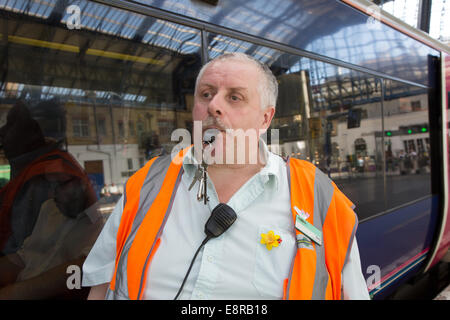 Ein Signal-Mann am Bahnhof bereitet seine Pfeife zu Blasen, um die Treiber wegzuziehen benachrichtigt. Brighton Stockfoto