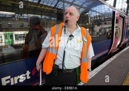 Ein Signalmann an einem Bahnhof bereitet sich darauf vor, Pfeifen zu blasen, um den Fahrer zu benachrichtigen, sich zu ziehen. Brighton Bahnhof Stockfoto