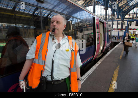 Ein Signal-Mann an einem Bahnhof statin bereitet seine Pfeife zu Blasen, um die Treiber wegzuziehen benachrichtigt. Bei Brighton Train Stat Stockfoto