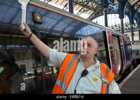 Ein Signal-Mann am Bahnhof bereitet seine Pfeife um den Fahrer wegzuziehen benachrichtigen zu blasen. Am Bahnhof von Brighton Stockfoto