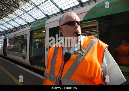 Ein Signal-Mann am Bahnhof von Brighton bereitet seine Pfeife zu Blasen, um die Treiber wegzuziehen benachrichtigt. Stockfoto