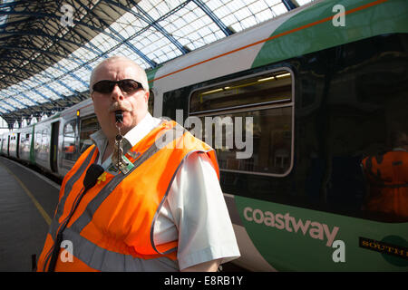 Ein Signal-Mann am Bahnhof von Brighton bereitet seine Pfeife zu Blasen, um die Treiber wegzuziehen benachrichtigt. Stockfoto