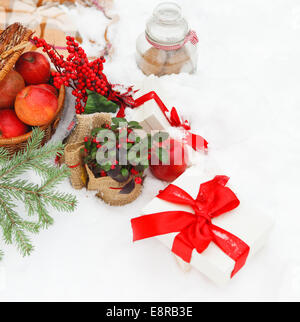 Weihnachten-Stillleben mit Weihnachtsschmuck, Cookies, Äpfel, präsentiert eingebettet in frischem Schnee Stockfoto