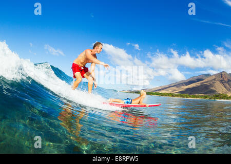 Vater und Sohn Surfen zusammen. Welle mit Surfbrett Tandem. Vaterschaft, Familie Spaß Outdoor-Lifestyle. Stockfoto