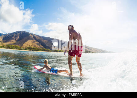 Vater und Sohn Surfen zusammen. Welle mit Surfbrett Tandem. Vaterschaft, Familie Spaß Outdoor-Lifestyle. Stockfoto