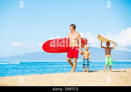 Vater und zwei Söhne gehen am Strand surfen Stockfoto