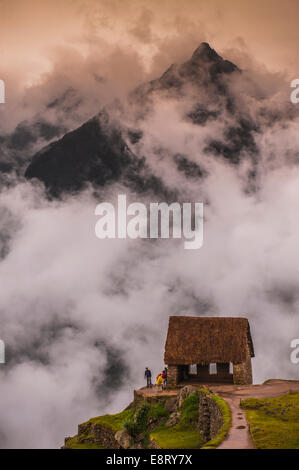 Wolken steigen um und über die Gatekeeper-Hütte in Machu Picchu, Peru. Der Aufstieg der peruanischen Hochland im Hintergrund Stockfoto