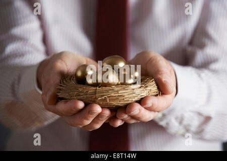 Geschäftsmann Holding Nest voller goldenen Eiern Stockfoto