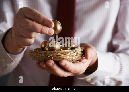 Geschäftsmann Holding Nest voller goldenen Eiern Stockfoto