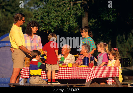 DREI-GENERATIONEN-FAMILIE BEIM PICKNICK TISCH CAMPING MIT ZELT Stockfoto