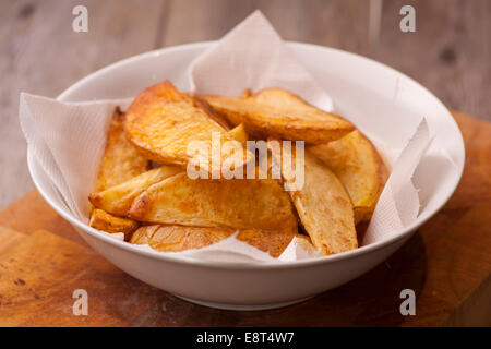 Eine Schüssel mit dicken Hackschnitzel in einer weißen Schüssel auf einer hölzernen Oberfläche gekocht. Stockfoto