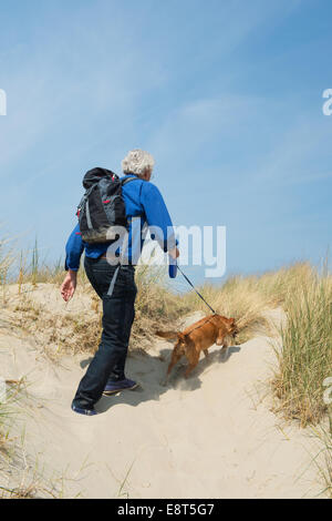 Senior woman Wandern mit Hund in den Dünen Stockfoto