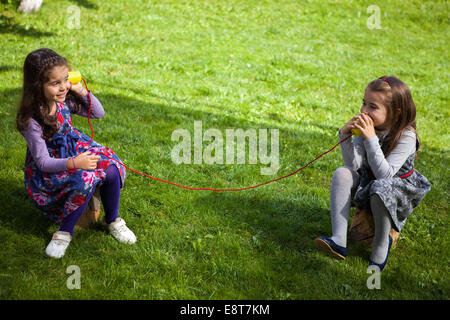 Zwei Mädchen spielen im Park mit Spielzeug Telefon Stockfoto