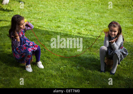 Zwei Mädchen spielen im Park mit Spielzeug Telefon Stockfoto