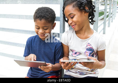 Afrikanische amerikanische Bruder und Schwester, die mit digitalen Tabletten Stockfoto