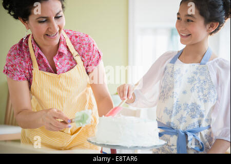 Hispanische Mutter und Tochter zusammen Kuchen dekorieren Stockfoto