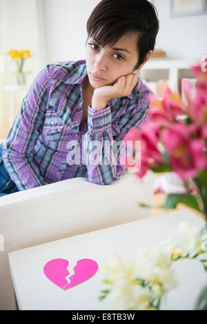 Trauriges gemischte Rasse Frau auf Sofa mit gebrochenen Herzen Stockfoto