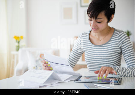 Gemischte Rassen Frau Zahlung von Rechnungen auf digital-Tablette Stockfoto