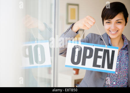 Gemischte Rassen Geschäftsfrau hält Schild "geöffnet" Stockfoto