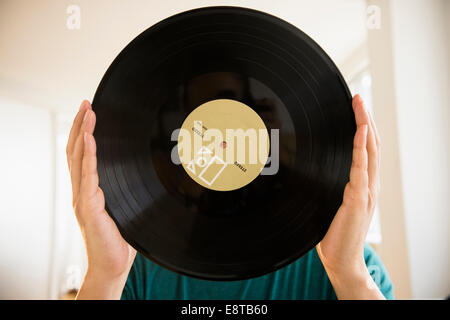 Gemischte Rassen Mann verdeckt Gesicht mit Vinyl-Schallplatte Stockfoto