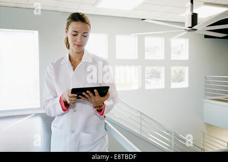 Kaukasische Arzt mit digital-Tablette in der Nähe von Geländer, Stockfoto